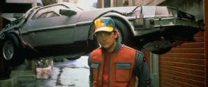 Screenshot from Back to the Future Part 2 where Marty is dressed as his younger self in front of the Delorean, which is lifting off
