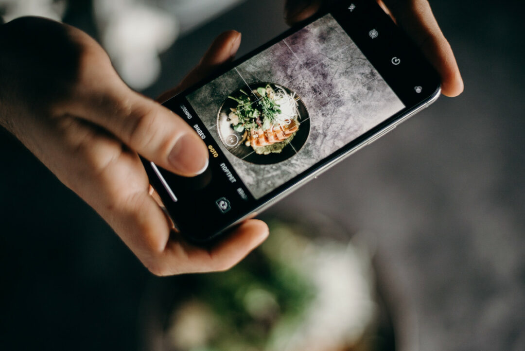 Overhead shot of a person taking a photo of a food dish with a smartphone