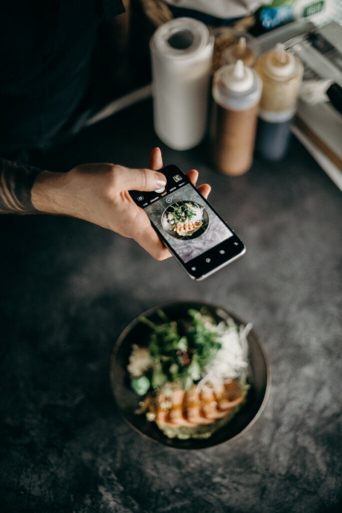 Overhead shot of a person taking a photo of a food dish with a smartphone